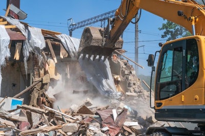 Process of demolition of old building dismantling. Excavator breaking house. Destruction of dilapidated housing for new development.