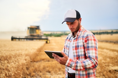 Farmer In Field Using App And Automation To Grow Wheat