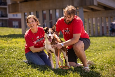 Purina Care volunteers with rescued dog on grassy lawn, smiling together