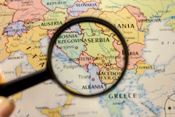 Magnifying glass revealing Balkan countries on a detailed European political map