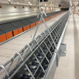 Metal wire conveyor rack suspended in industrial facility with blue components