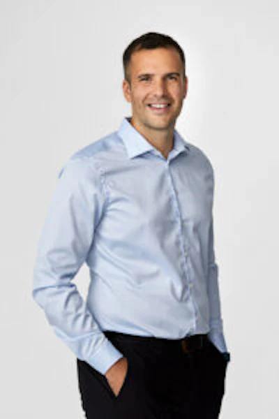 Smiling professional in light blue dress shirt against white background