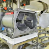 Industrial mixing machine with worker in bright yellow protective suit