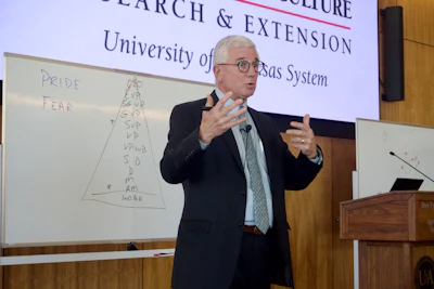 Speaker presenting research lecture with whiteboard diagram at University of Texas System