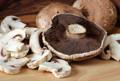 Fresh portobello and white button mushrooms sliced on wooden cutting board