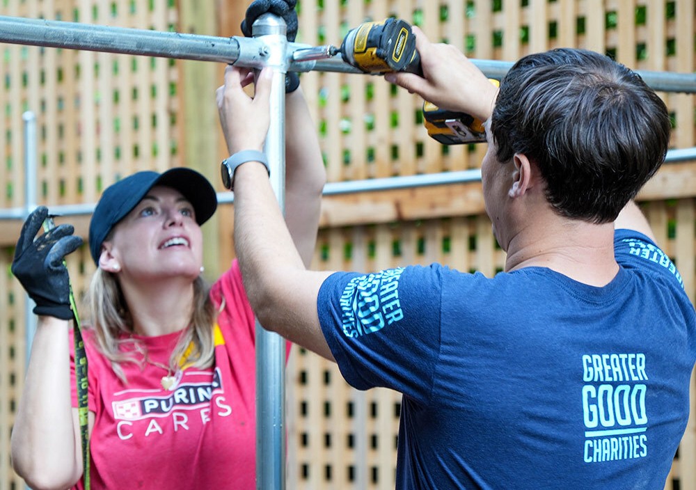 Volunteers in Purina Cares and Greater Good Charities shirts collaborating on construction project