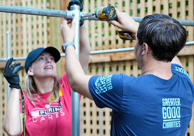 Volunteers in Purina Cares and Greater Good Charities shirts collaborating on construction project