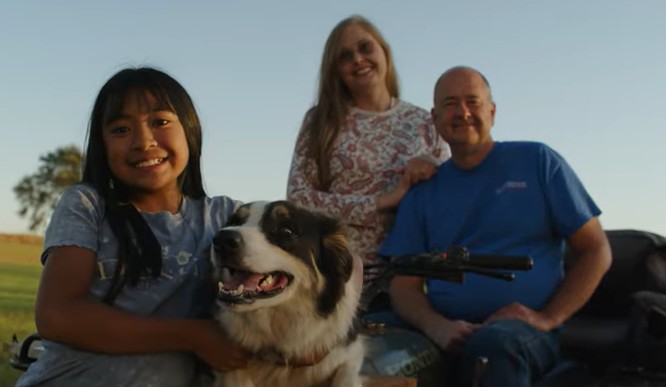 Smiling family with young girl, dog, and adults outdoors at sunset