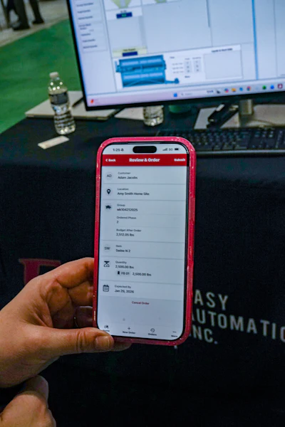 Mobile phone displaying order details with computer screen and workplace background