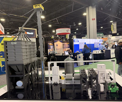 Industrial machinery model display at trade show with gray equipment and green forklift