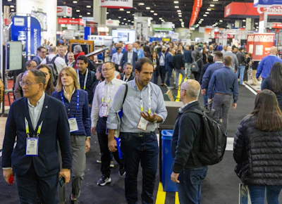 Crowded trade show floor with professionals networking and walking between exhibition booths