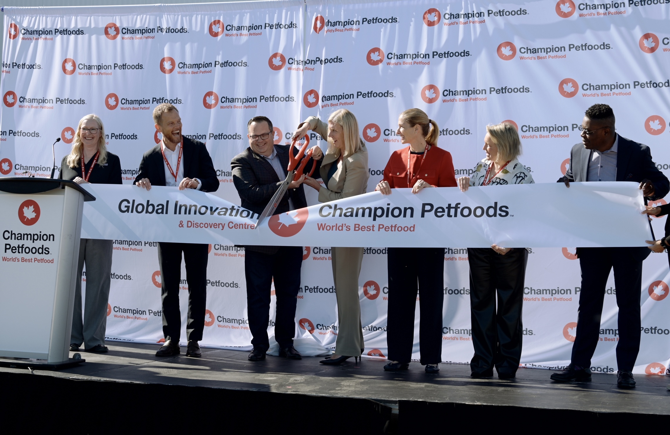 Champion Petfoods Global Innovation Discovery Center ribbon-cutting ceremony with executives and officials on stage