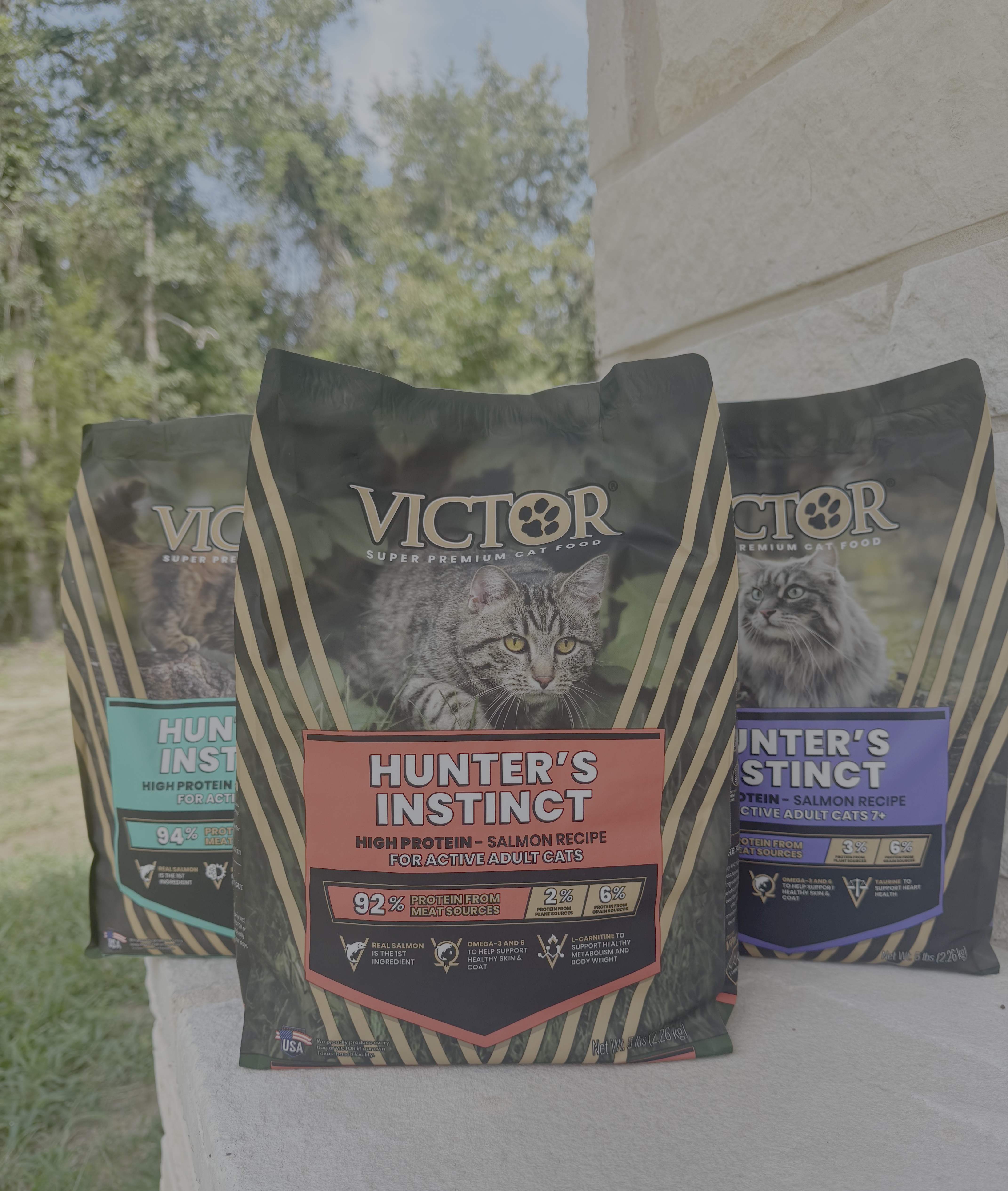 Three Victor Super Premium cat food bags featuring Hunter's Instinct formula with salmon recipe displayed outdoors