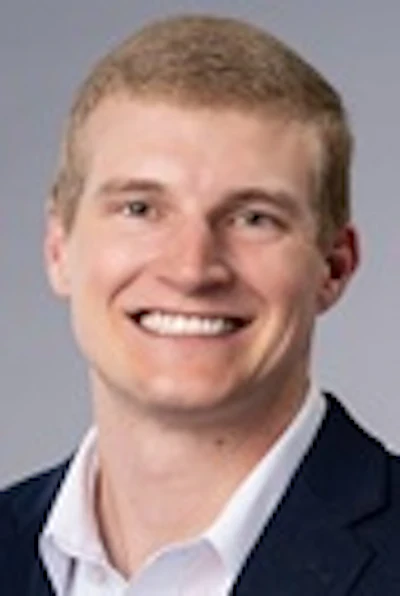 Professional headshot of smiling man in dark blazer and light blue shirt