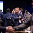 Business professionals networking at a conference event with blue display screen in background