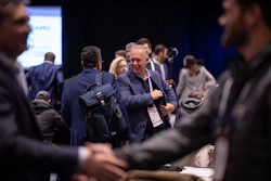 Business professionals networking at a conference event with blue display screen in background