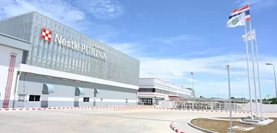 Nestlé Purina manufacturing facility with red checkered logo on white building facade and flags in foreground