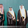 Four men in traditional Saudi Arabian formal attire posing together against a turquoise background
