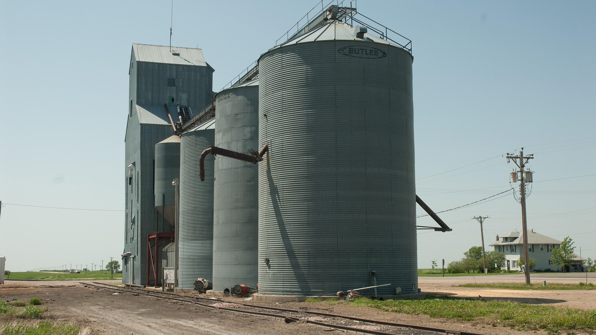Rural grain elevator facility with metal storage silos and concrete tower structure