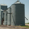 Rural grain elevator facility with metal storage silos and concrete tower structure