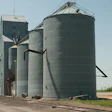 Rural grain elevator facility with metal storage silos and concrete tower structure