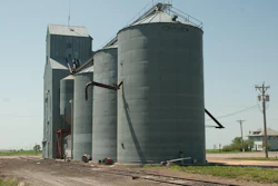 Rural grain elevator facility with metal storage silos and concrete tower structure