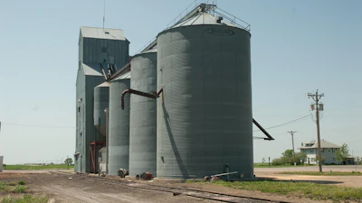 Rural grain elevator facility with metal storage silos and concrete tower structure