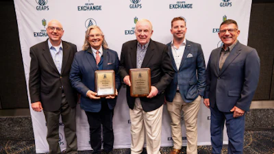 Five men in business attire holding wooden award plaques at a corporate awards ceremony with branded backdrop.