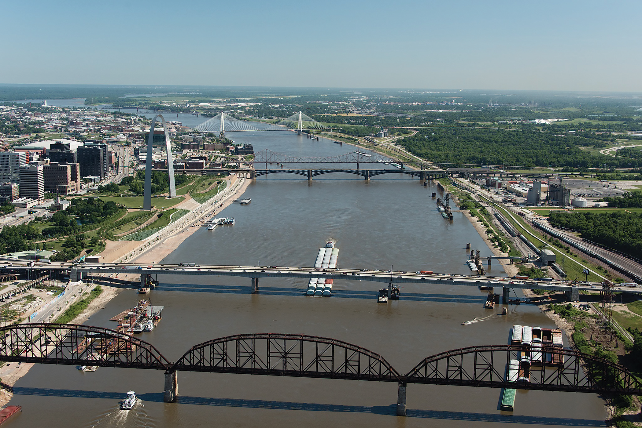 Aerial view of Detroit skyline with multiple bridges crossing the Detroit River, showing urban development and waterfront infrastructure.