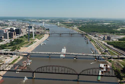 Aerial view of Detroit skyline with multiple bridges crossing the Detroit River, showing urban development and waterfront infrastructure.