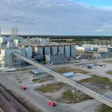 Large grain elevator facility with cylindrical storage silos, industrial buildings, and railroad tracks in rural landscape