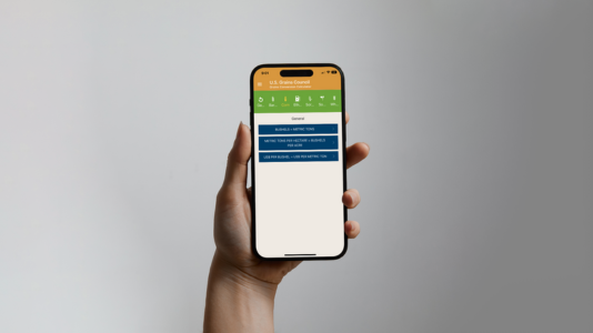 Hand holding smartphone displaying green and blue app interface with navigation menu