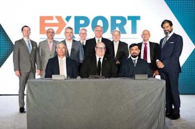Business executives and professionals posing at EXPORT corporate event with branded backdrop