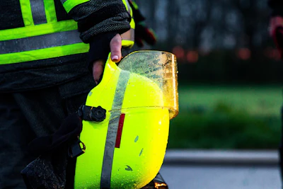 Worker in safety vest holding wet neon yellow hard hat with reflective stripes