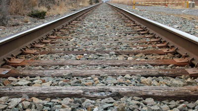 Railroad tracks with wooden ties and gravel ballast extending into the distance