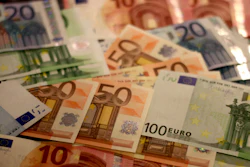 Scattered Euro banknotes in various denominations including €10, €20, €50, and €100 notes displayed on a surface