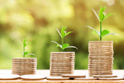 Three progressively taller coin stacks with green plant shoots symbolizing financial growth and investment success
