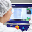 Worker in protective gear operating TOLEDO industrial inspection machine with quality control display showing accepted and rejected items