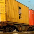 Colorful shipping containers stacked on railway cars, including red, yellow, and orange units with company markings.