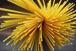 Yellow radial starburst with cylindrical strands radiating from center against dark background