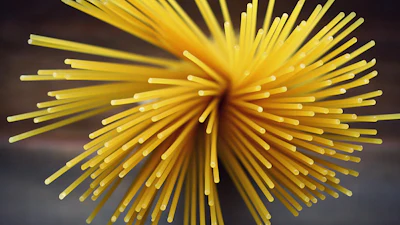 Yellow radial starburst with cylindrical strands radiating from center against dark background