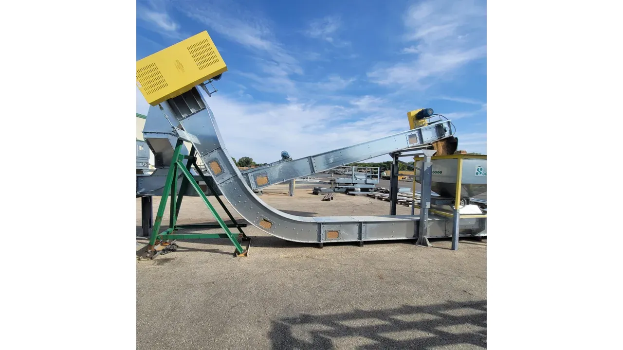 Industrial concrete mixer and conveyor system with yellow hopper and green support frame at outdoor facility