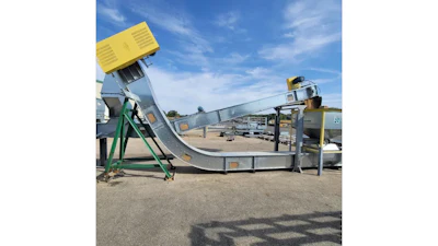 Industrial concrete mixer and conveyor system with yellow hopper and green support frame at outdoor facility