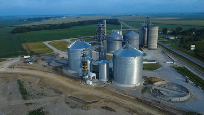 Aerial view of grain storage facility with cylindrical silos and processing equipment in rural farmland