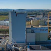 Industrial manufacturing facility with blue silos and fixkraft signage in rural landscape with mountains